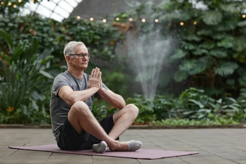 Older man practicing yoga outdoors, looking calm and fit, demonstrating physical wellness and balance in later years.