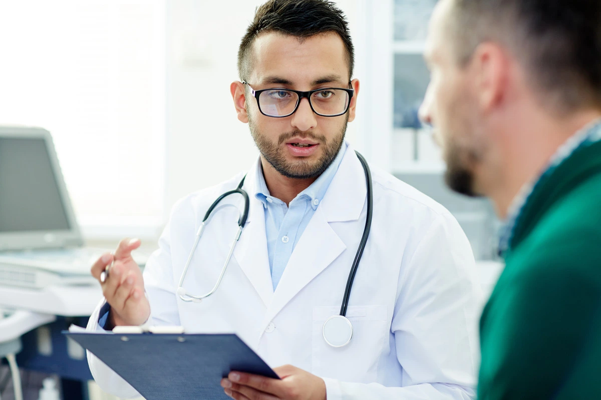 Male doctor in a white coat speaking to a patient, offering professional advice and information about prostate-related health concerns.