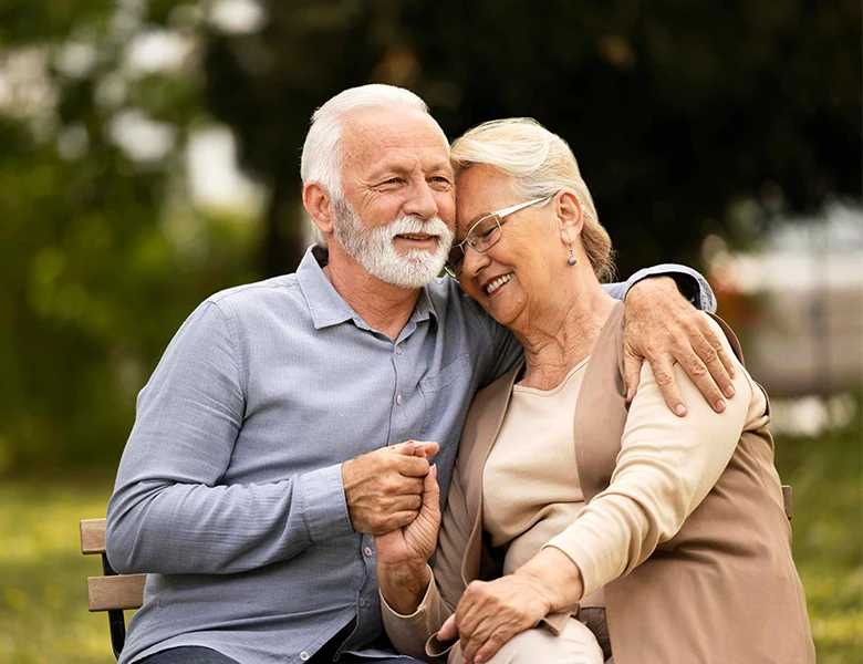 Two happy elderly people embracing each other, smiling warmly, symbolizing comfort and care.